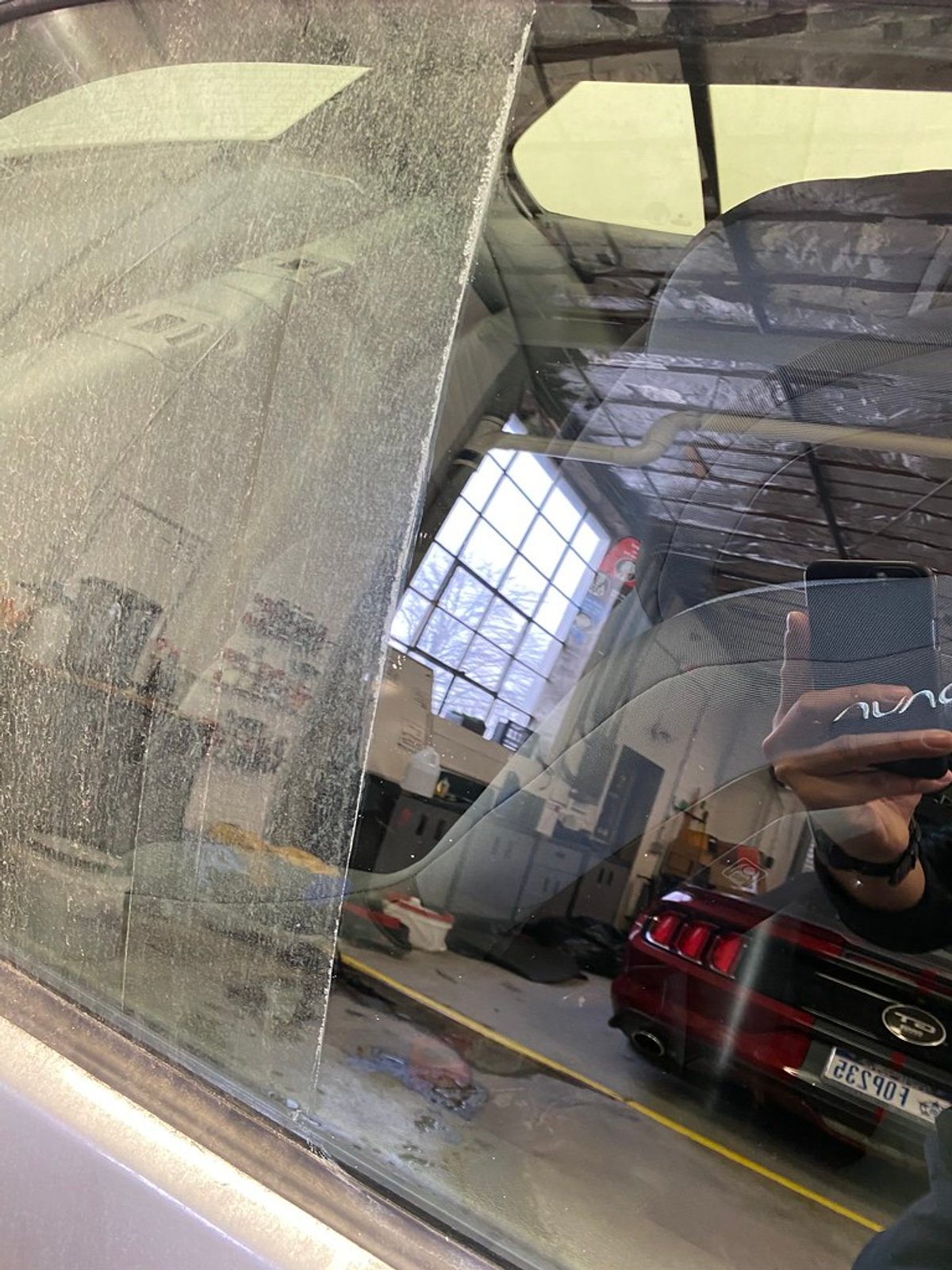 Rear window of a BMW M3 with a sharp line between the half still covered in water spots and the half already cleaned