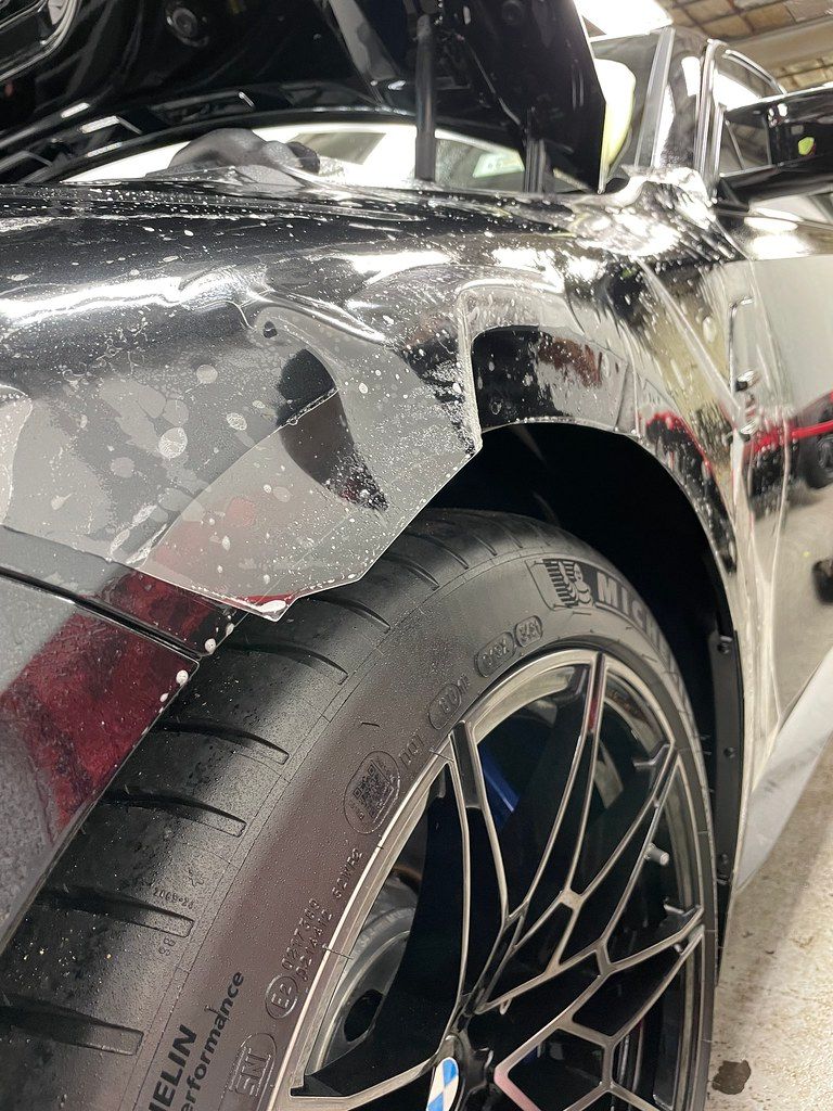 Paint protection film being worked onto a BMW M4 fender with slip solution