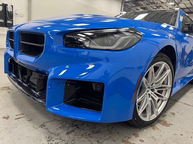 Close-up of a Zandvoort Blue BMW M2 front end in the shop showing a flawless PPF installation on the bumper and fender.