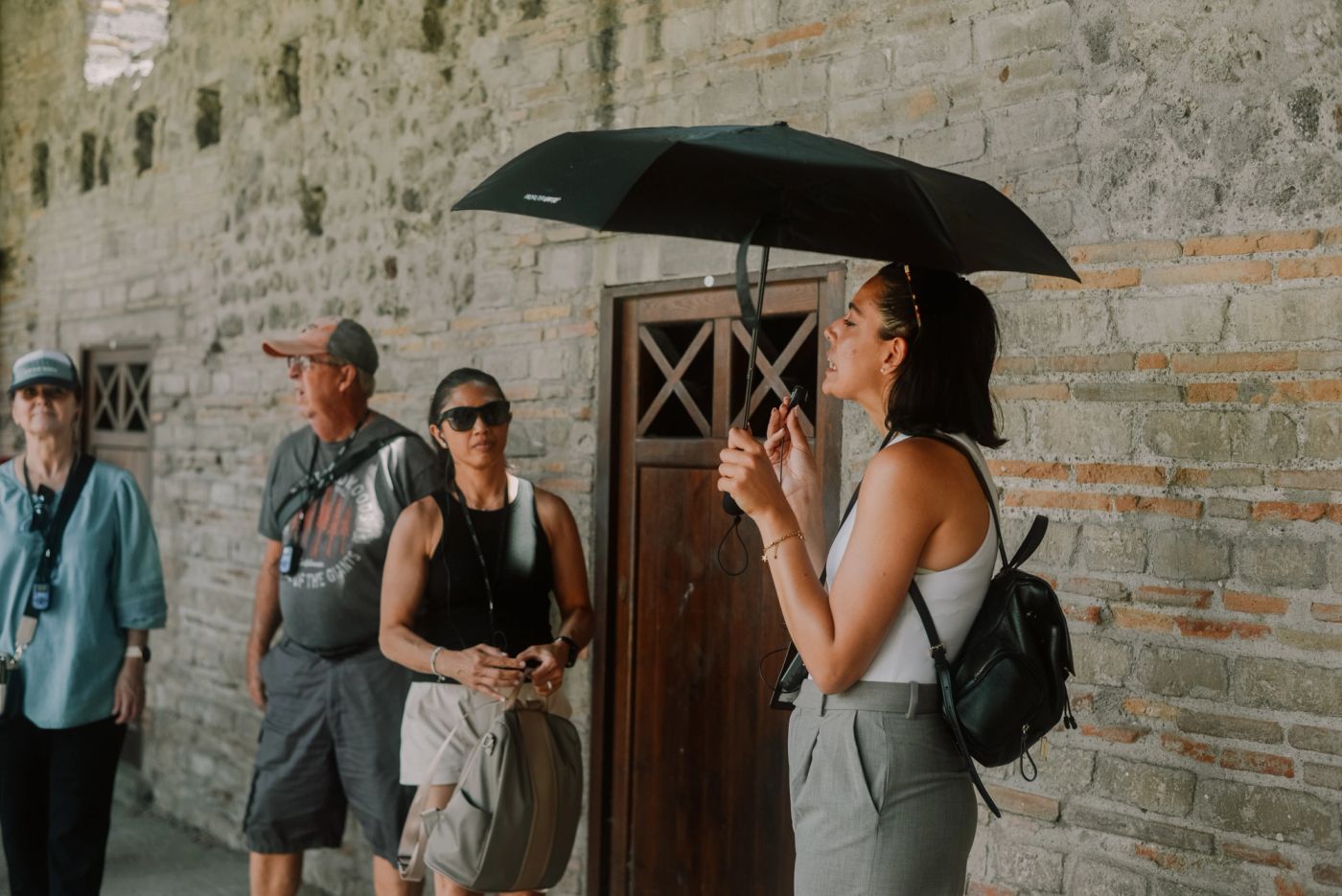 Tour guide with a black umbrella talking to the group in an alley