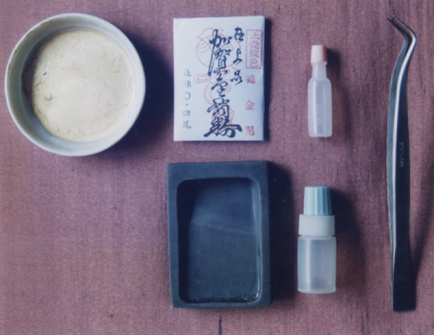 Materials for painting in pure gold ink: porcelain mixing bowl, 24-karat gold powder, ink stone, two bottles of fluids, and a tweezer (Photo: Kenichi Arakawa)