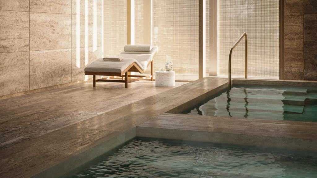 Spa with a travertine plunge pool and a lounge chair in soft natural light.