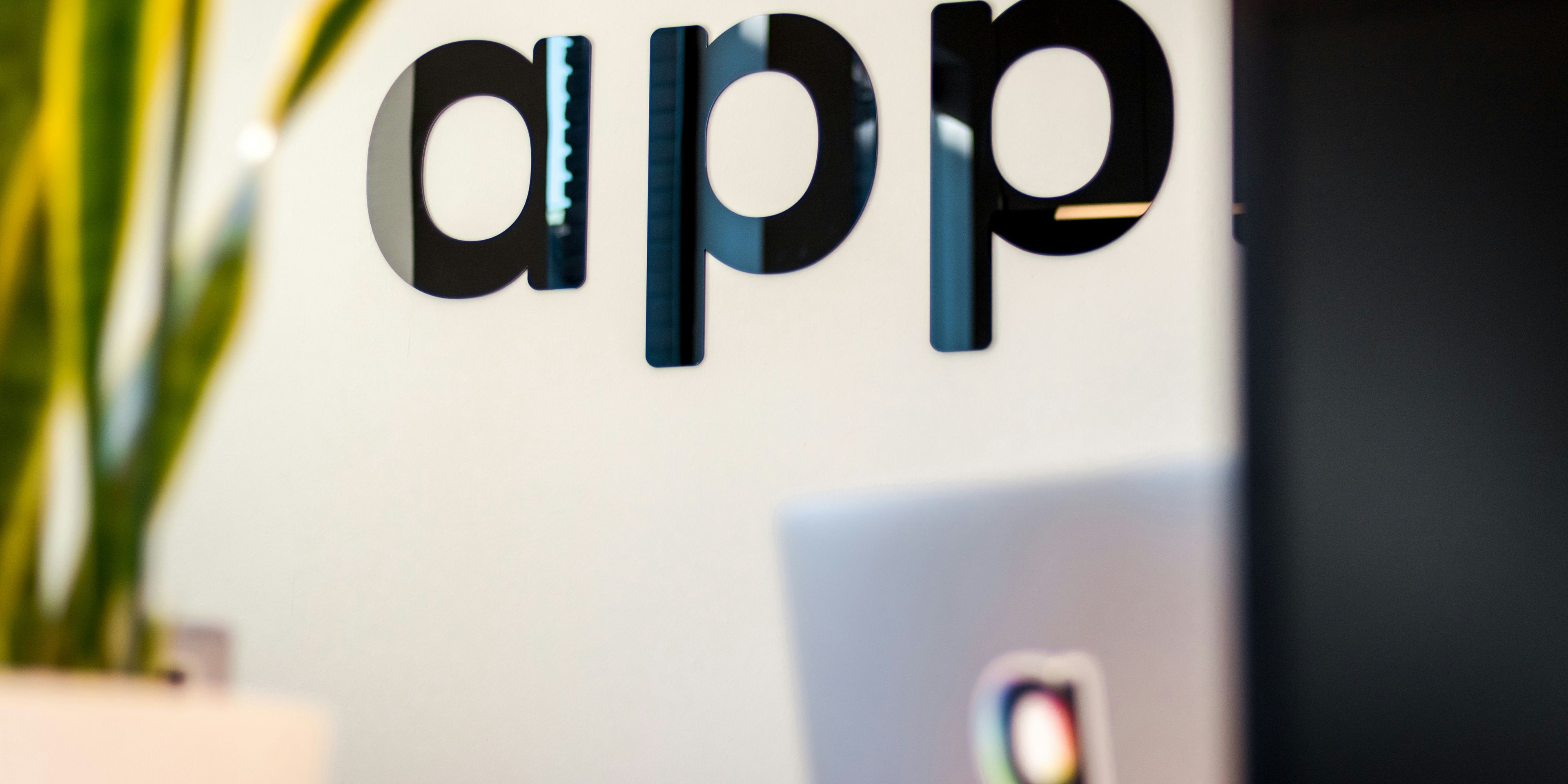 The word "app" written on a glass wall next to a laptop.