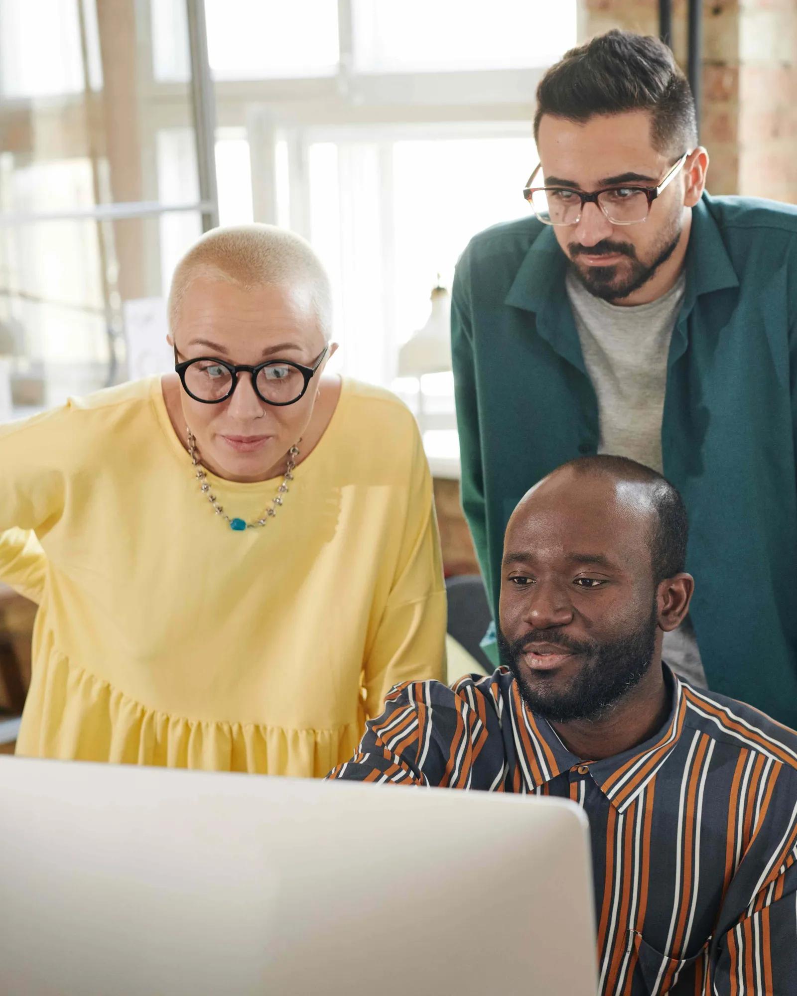 Three people looking at a computer together.