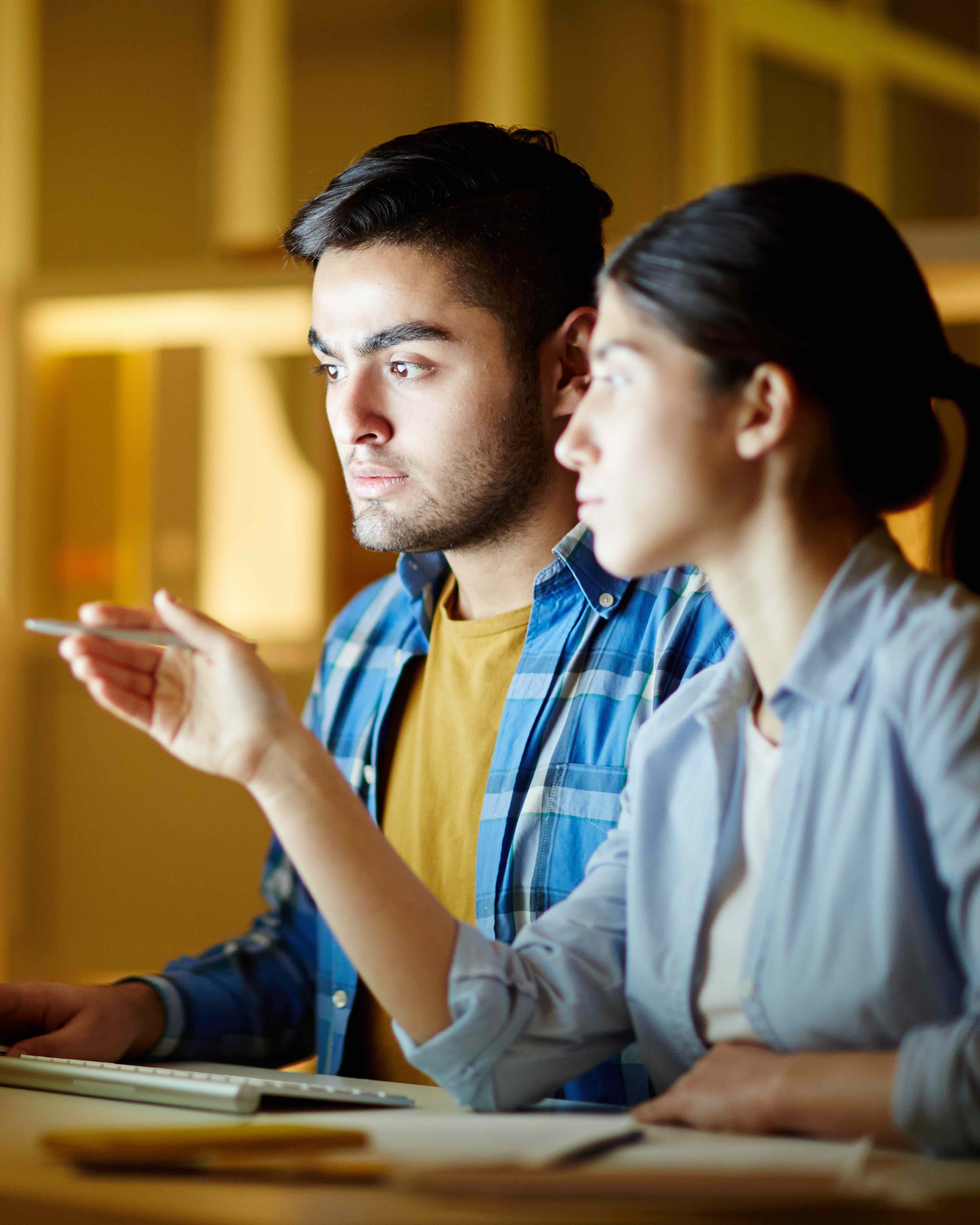 Two people looking at and pointing to screen.