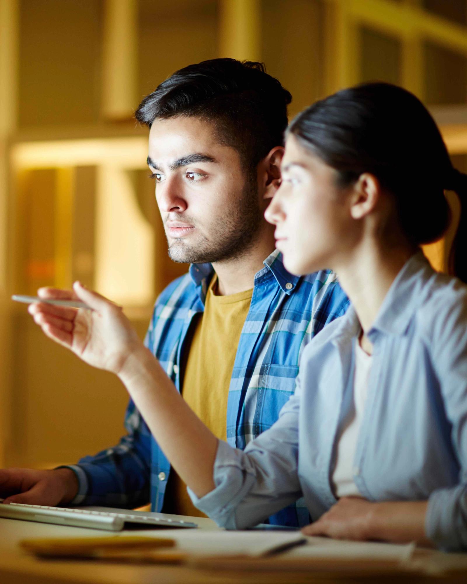 Two people looking at and pointing to screen.
