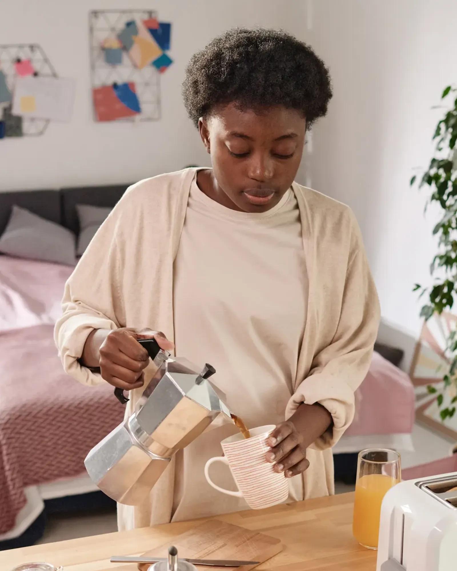 Image of a young woman pouring coffee into a mug.