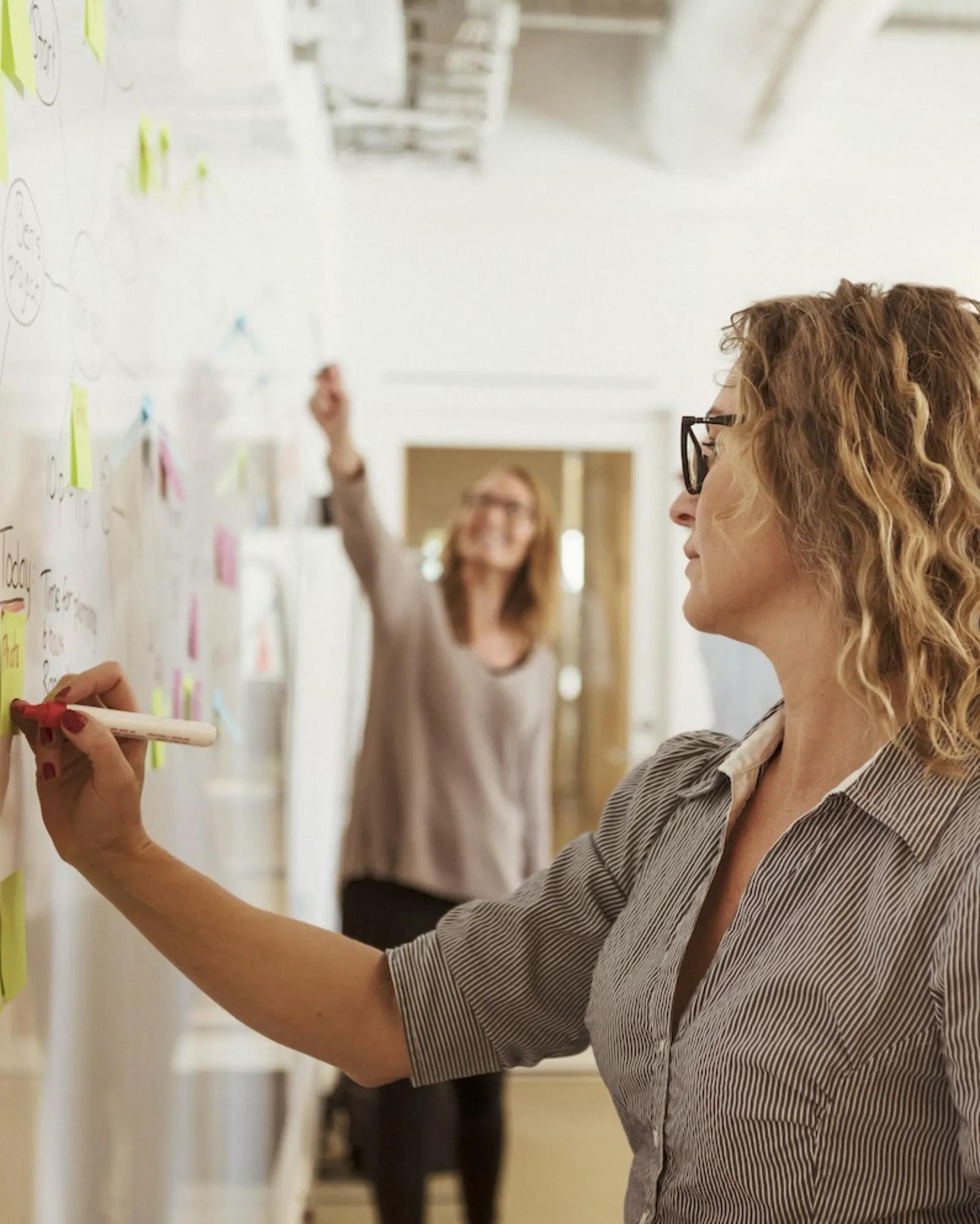 Woman writing ideas on a whiteboard.