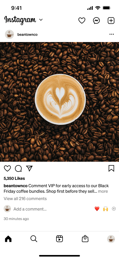 A cup of coffee with heart-shaped latte art rests on a bed of roasted coffee beans.