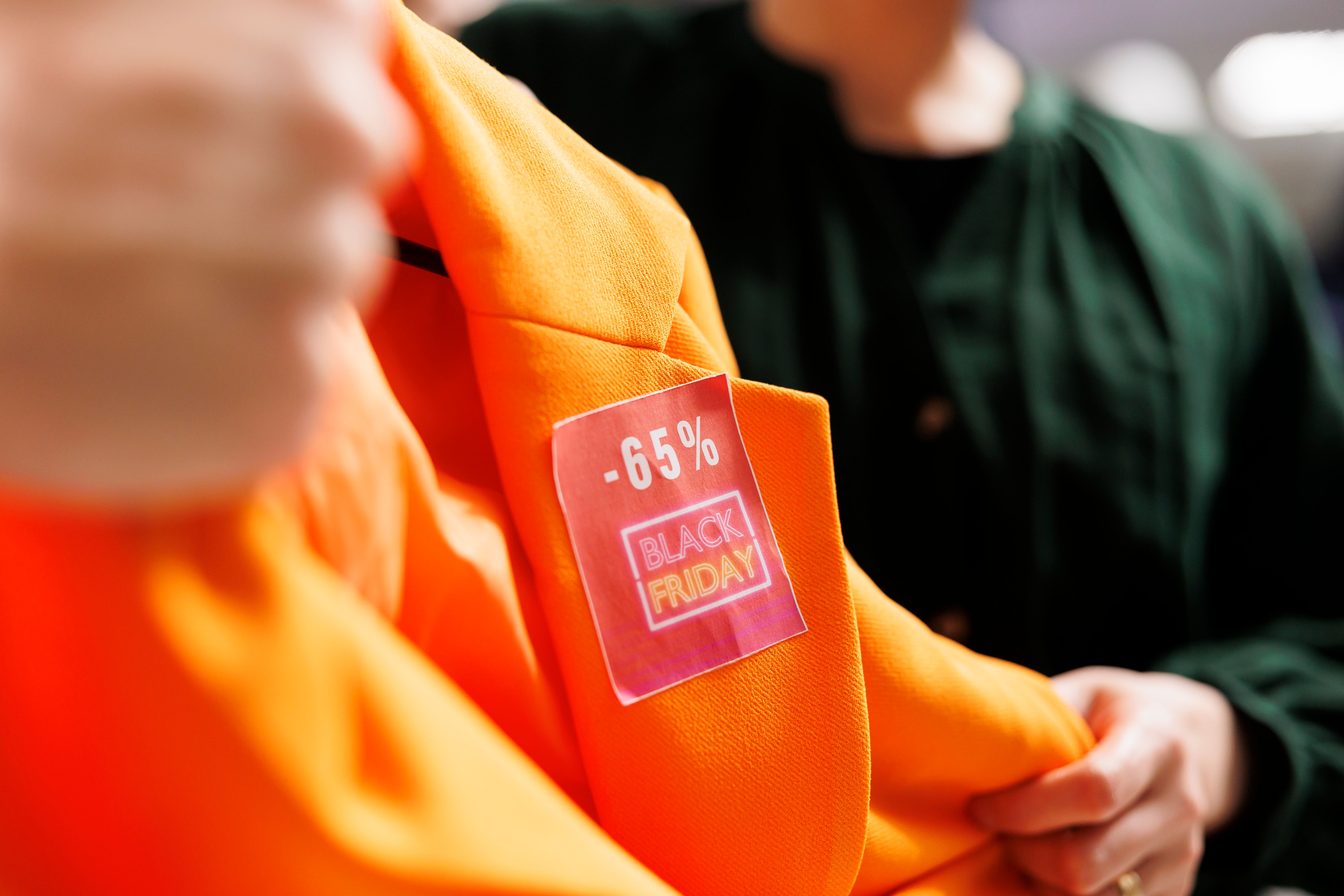 Close-up of an orange jacket with a pink "Black Friday -65%" discount sticker.