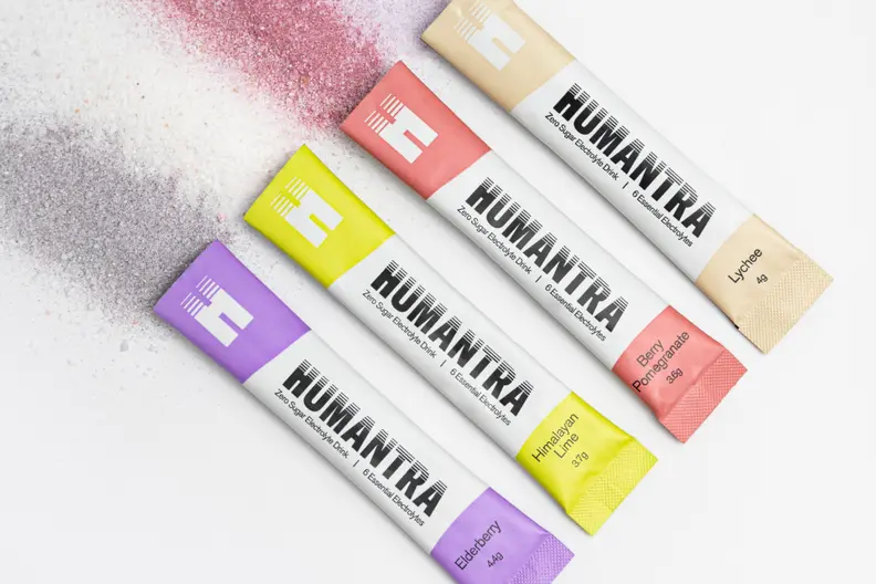 Four HUMANTRA zero sugar electrolyte drink sachets in assorted colors with scattered powders.