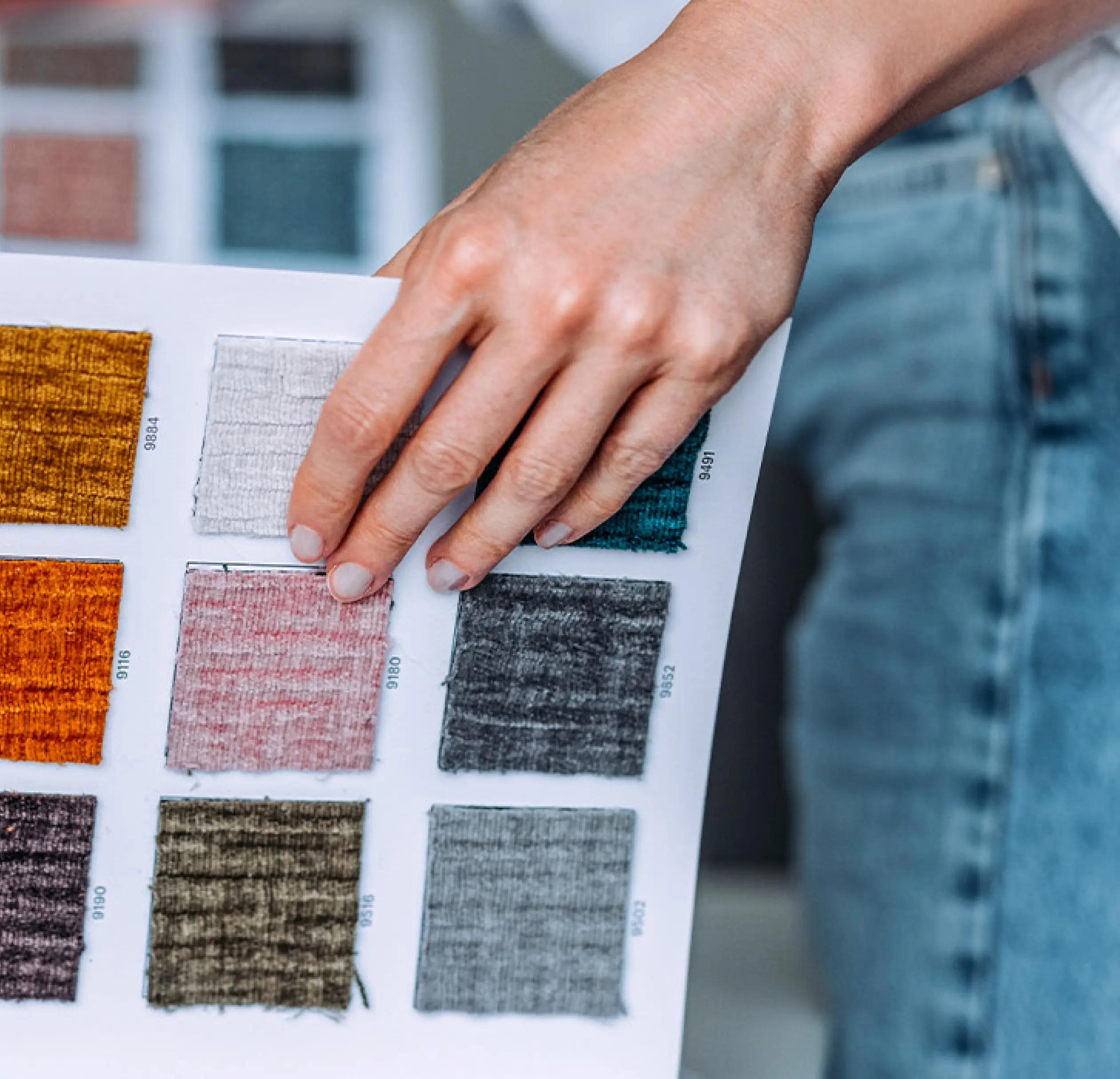 A persons hand shown as they browse some fabric books