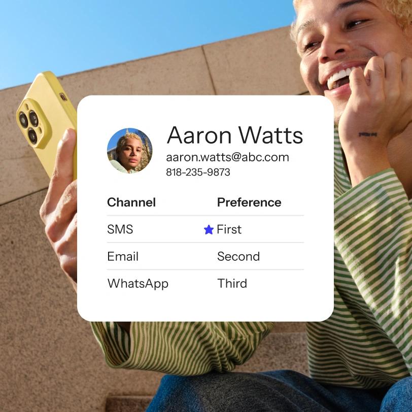 Smiling person checks a phone beside a contact card listing SMS, email, and WhatsApp preferences.