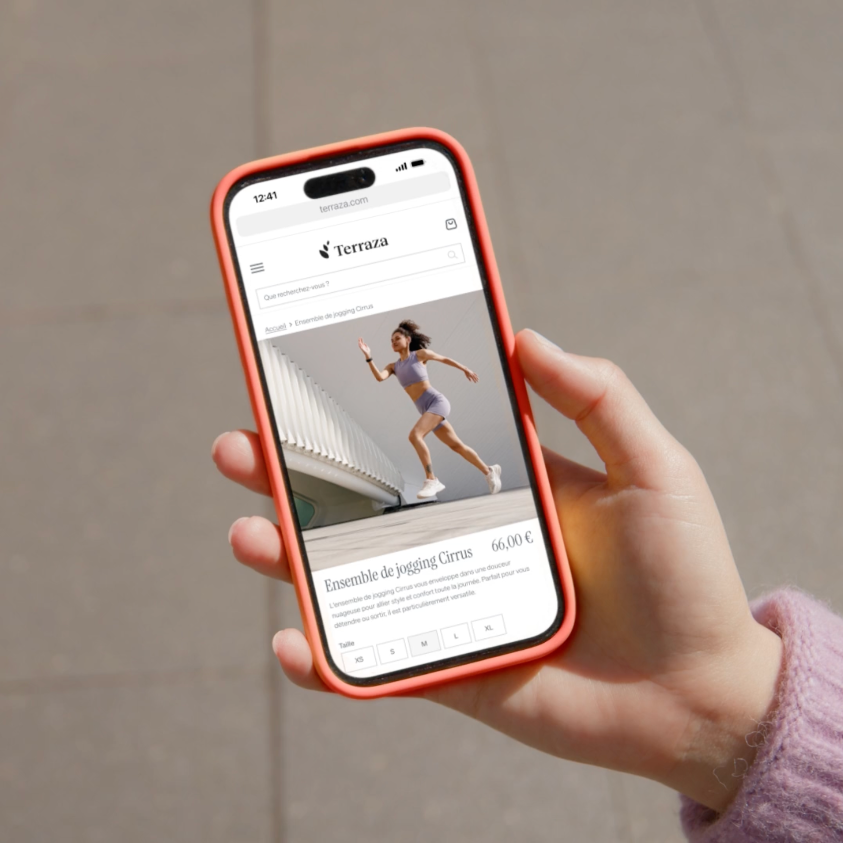 Hand holding orange smartphone displaying Terraza e-commerce page with athletic wear.