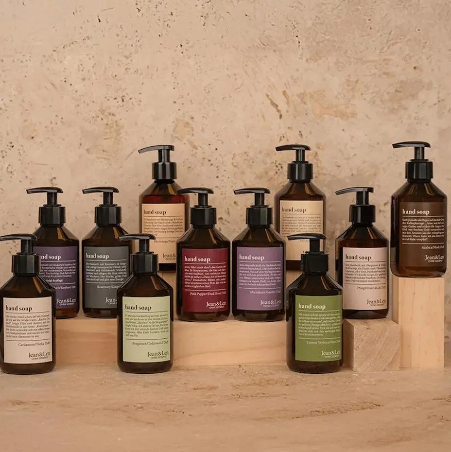 Mehrere Flaschen Handseife von Jean&Len mit verschiedenen Etikettenfarben auf einem Holzpodest.