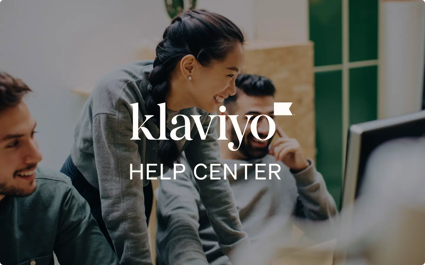 Lächelnde Menschen arbeiten zusammen an einem Computer, überlagert mit dem Text "Klaviyo Help Center".