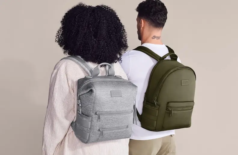 Two people seen from behind, one wearing a grey backpack and the other an olive green backpack.