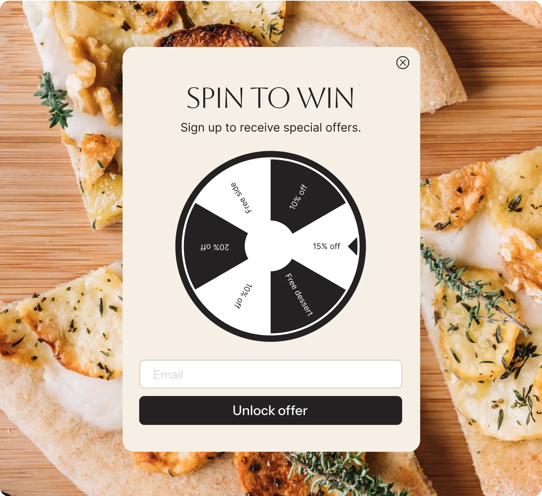 Pop-up with a 'Spin to win' wheel offering special discounts and rewards in exchange for email sign-up. Prizes on the wheel include 10% off, 15% off, 20% off, free dessert, and free side. Background features flatbread or pizza slices on a wooden surface. A field to enter email and 'Unlock offer' button are at the bottom.