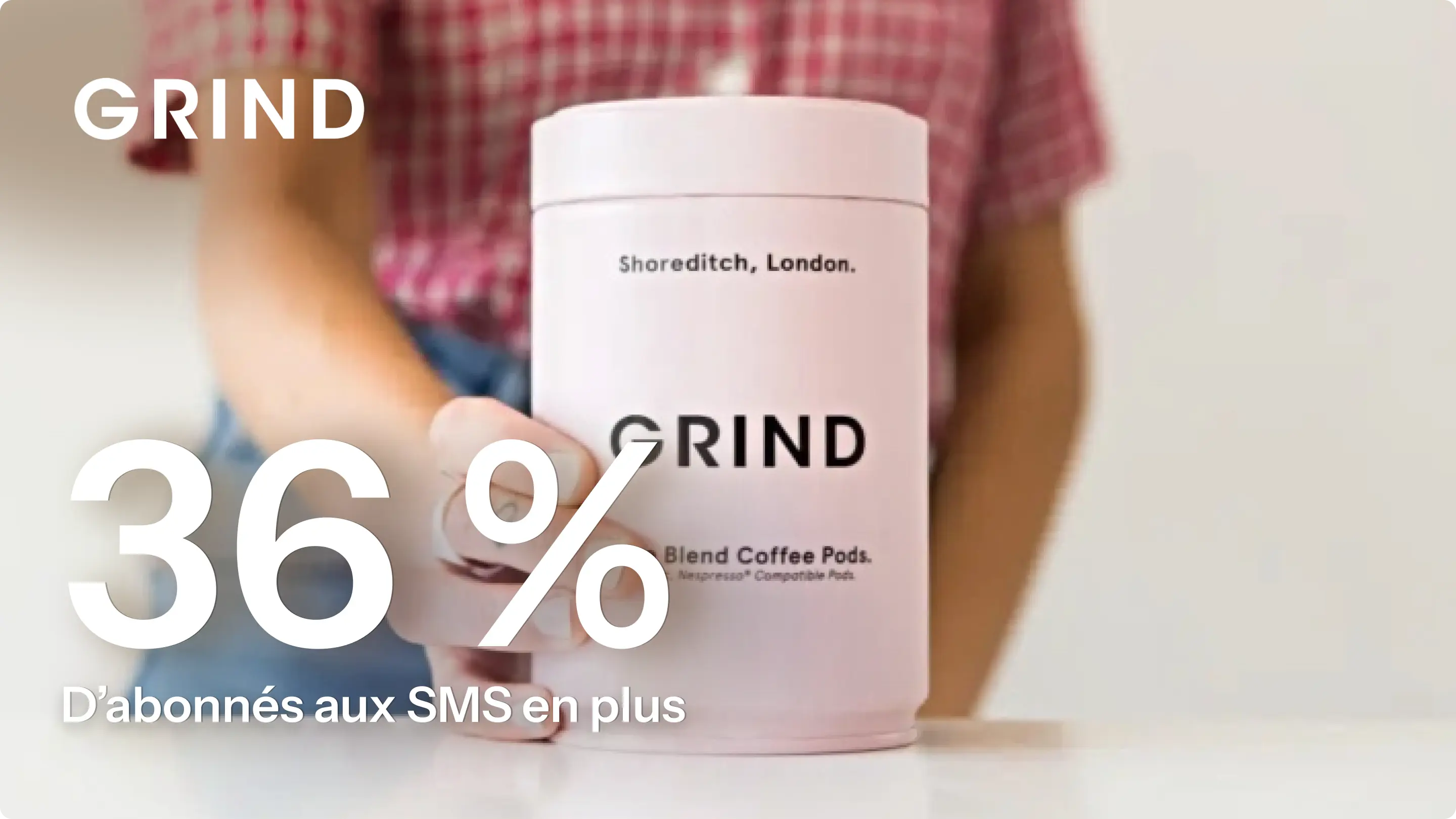Boîte de capsules de café GRIND tenue par une personne. Texte : "36 % d'abonnés aux SMS en plus".