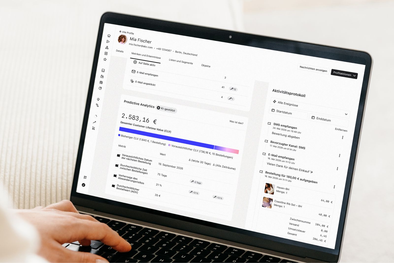 Person using a laptop displaying a customer profile, predictive analytics, and activity log.