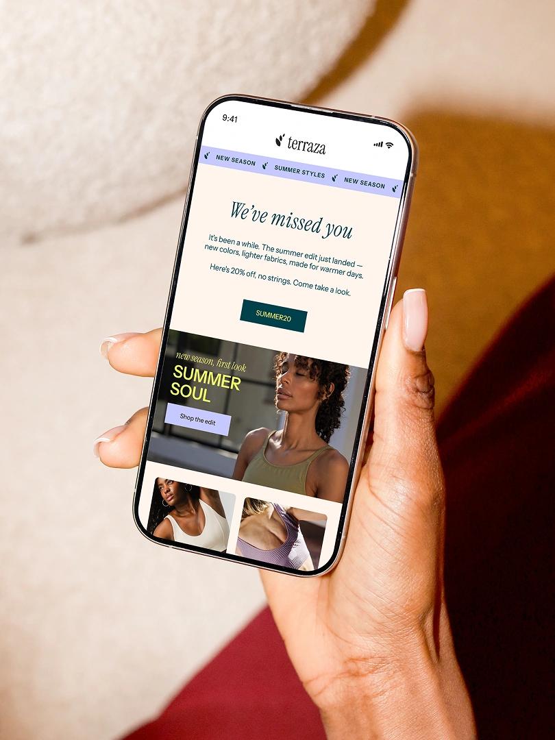 Person holding a smartphone displaying a Terraza summer fashion promotion and discount code.