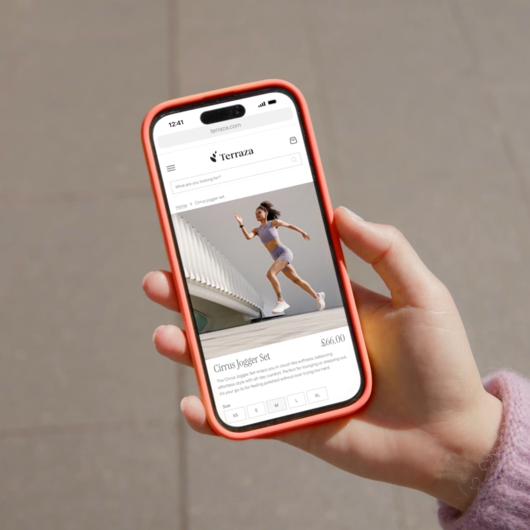 Hand holding a smartphone with an orange case, displaying an e-commerce product page featuring a woman running in a purple athletic outfit.
