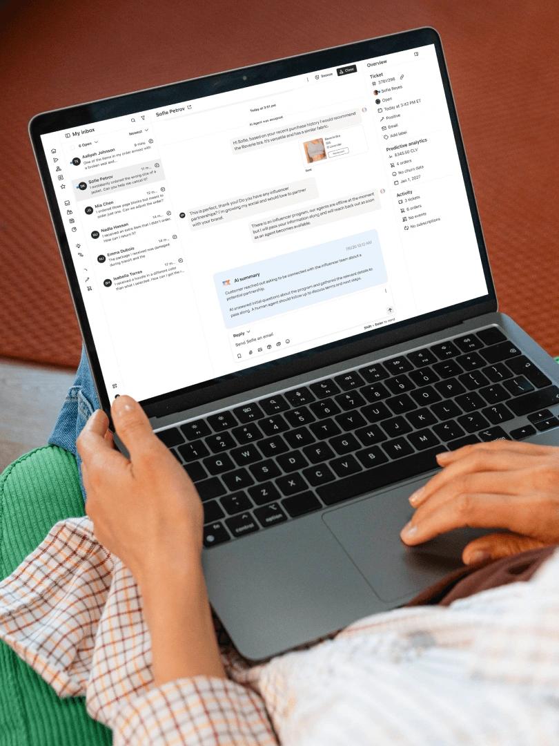 Person using a laptop displaying a customer support inbox with an AI-generated conversation summary.