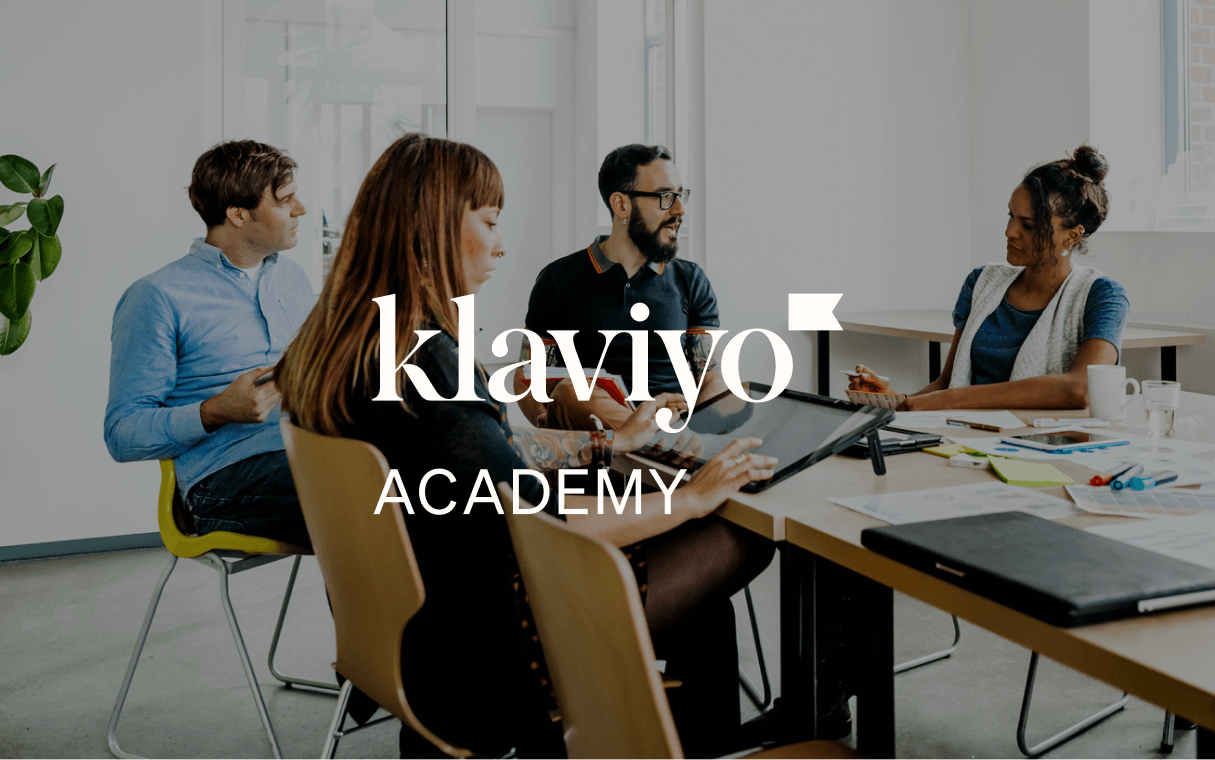 Quattro colleghi collaborano attorno a un tavolo da conferenza, con il logo di Klaviyo Academy in sovrimpressione.