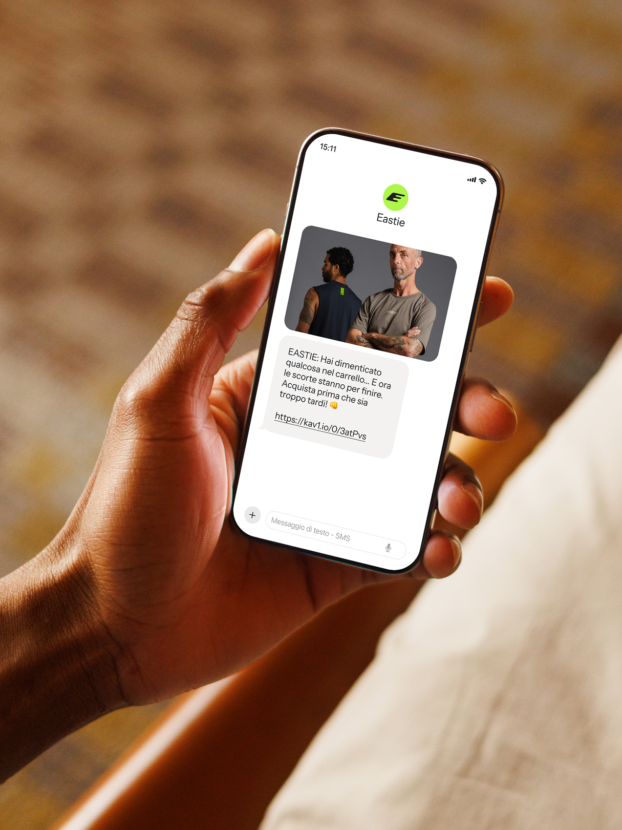 Person holding a smartphone displaying an Eastie reminder text with a clothing product photo and link.