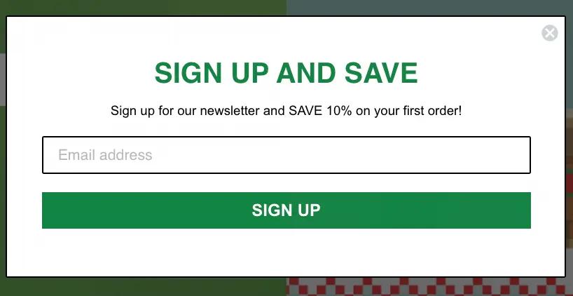 Image shows a minimalist sign-up form from the Official Shop of Minecraft. In green capital letters on a white background, the form reads, “Sign up and save: sign up for our newsletter and SAVE 10% on your first order!” Below the copy is a field where the site visitor can enter their email address, followed by a green CTA button that reads, “sign up.”