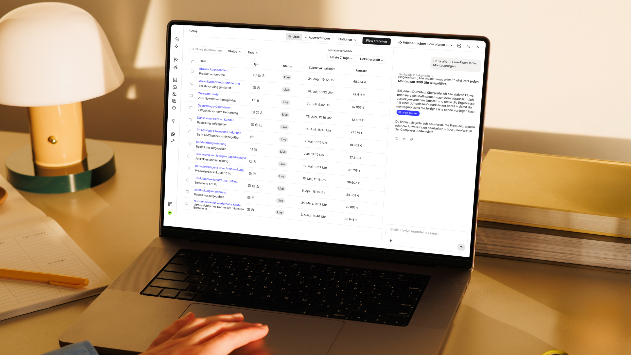 Laptop mit einem Dashboard für Marketing-Automatisierung neben einer Lampe, einem Notizbuch und gestapelten Büchern.