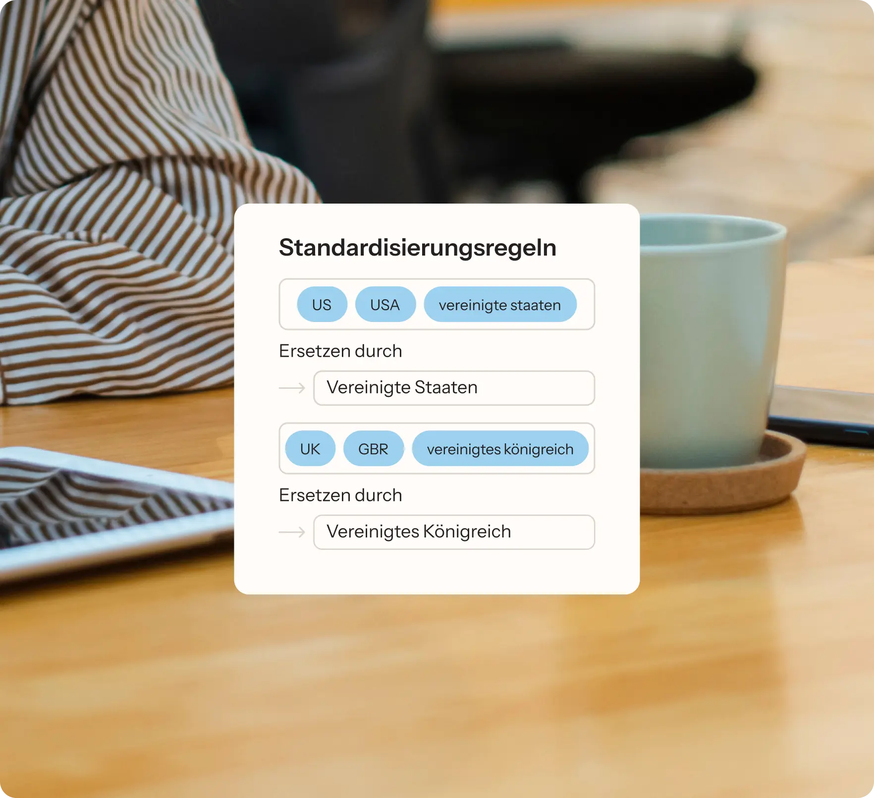 Standardisierungsregeln auf einem Bildschirm, daneben eine Person in gestreiftem Hemd, ein Tablet und eine Tasse auf einem Tisch.