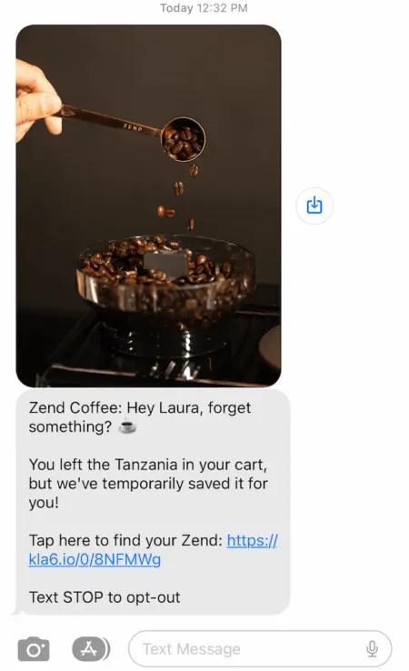Image shows an abandoned cart text from Zend Coffee which reads, “Hey Laura, forget something? You left the Tanzania in your cart, but we’ve temporarily saved it for you! Tap here to find your Zend.” The text includes a photo of someone scooping coffee beans into a grinder at the top, and a link to the recipient’s cart at the bottom.