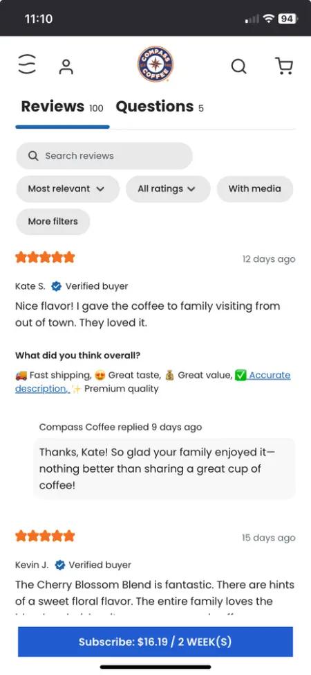 Image shows a mobile screenshot of a list of reviews with star ratings on a product page for Compass Coffee. At the top, the user can see there are 100 reviews for the product, and there are buttons to filter results by most relevant, media, and more filters. Underneath are two 5-star reviews, the top of which has additional emoji icons associated with fast shipping, great taste, great value, etc.