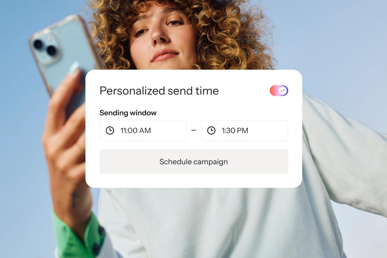 Woman holding a smartphone behind a personalized send time scheduling interface.