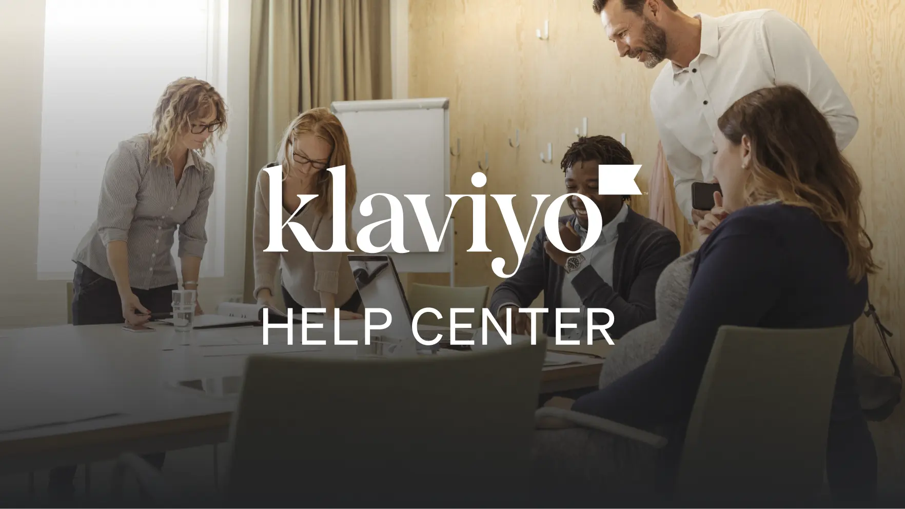 Klaviyo-Logo über einer Gruppe von Menschen, die an einem Tisch in einem Besprechungsraum arbeiten. Text: "Help Center".