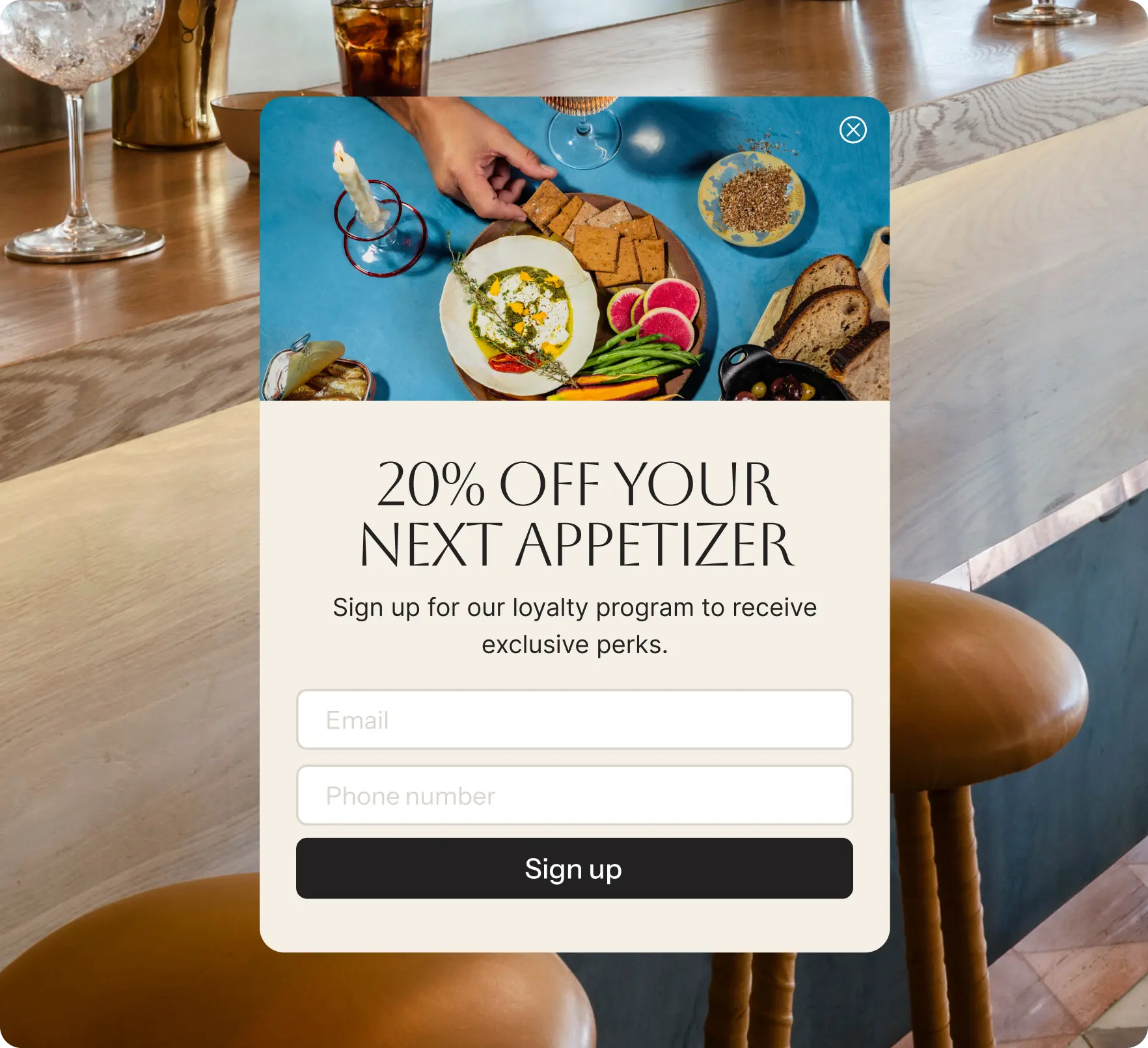 A pop-up sign-up form on a restaurant bar background offering ‘20% off your next appetizer’ for signing up for a loyalty program with fields to enter email and phone number.