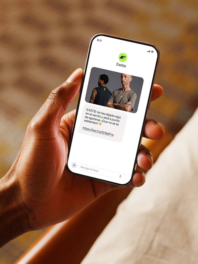 Person holding a smartphone displaying an Eastie reminder text with a clothing product photo and link.