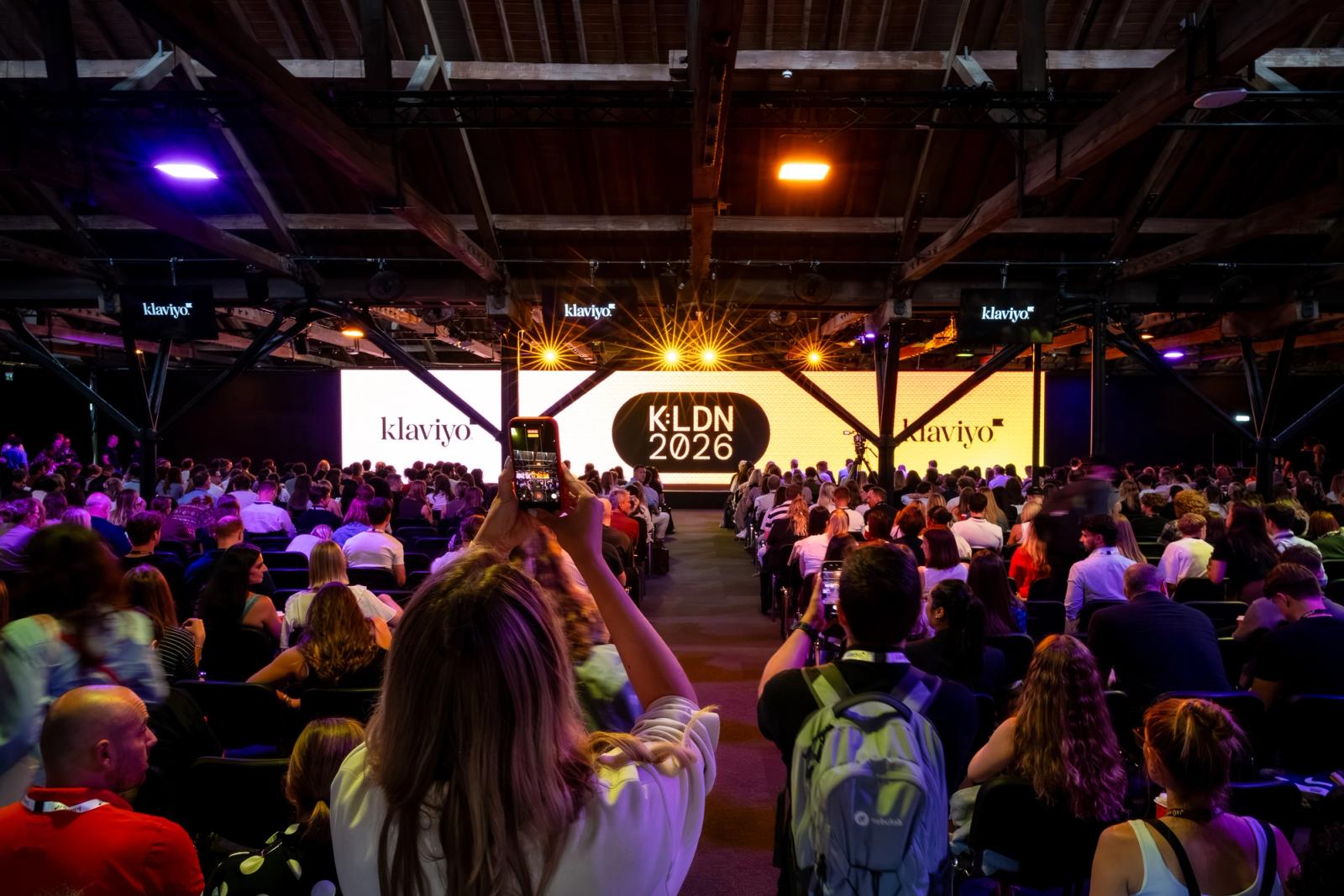 Large crowd at a Klaviyo event, with screens displaying 'Klaviyo' and 'KLDN 2026', and attendees taking photos.