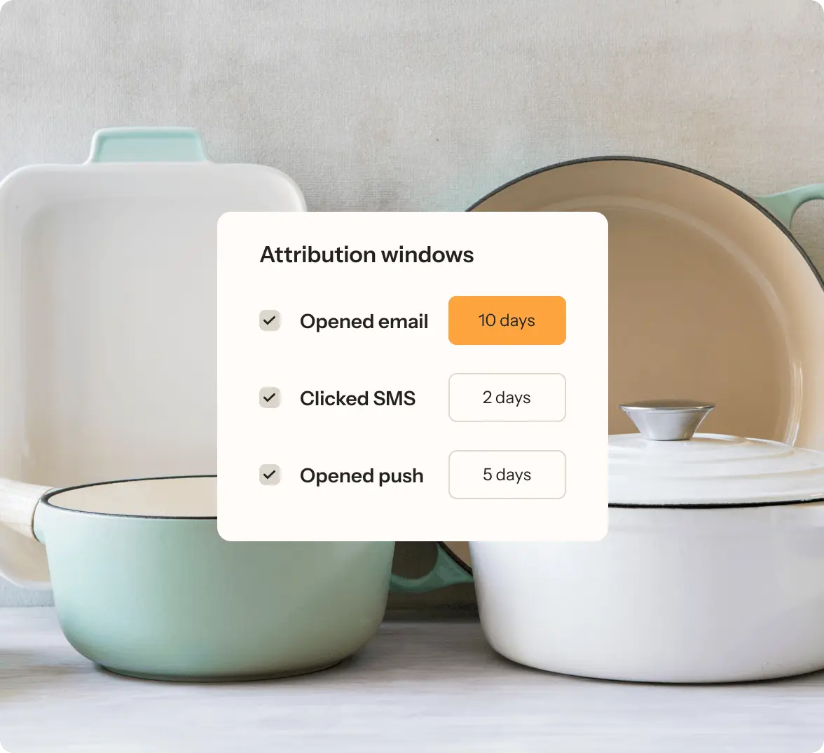Custom attribution windows in Klaviyo including Opened Email within 10 days, Clicked SMS within 2 days and Opened push within 5 days with kitchen cookware in background