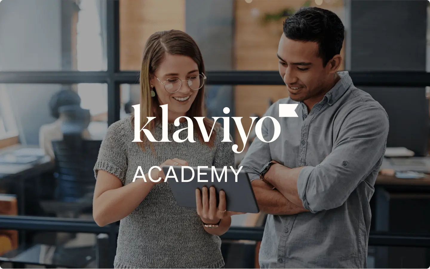 Due colleghi che collaborano su un iPad in un ufficio con testo in sovrimpressione “Klaviyo Academy”.