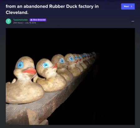 Image shows a screenshot of a creepy photo subscribers land on when they click one of the “trick” links in the Minor Figures Halloween marketing email. The photo, titled “abandoned rubber duck factory in Cleveland,” shows a dozen rubber duckies lined up on a wooden shelf in the night.