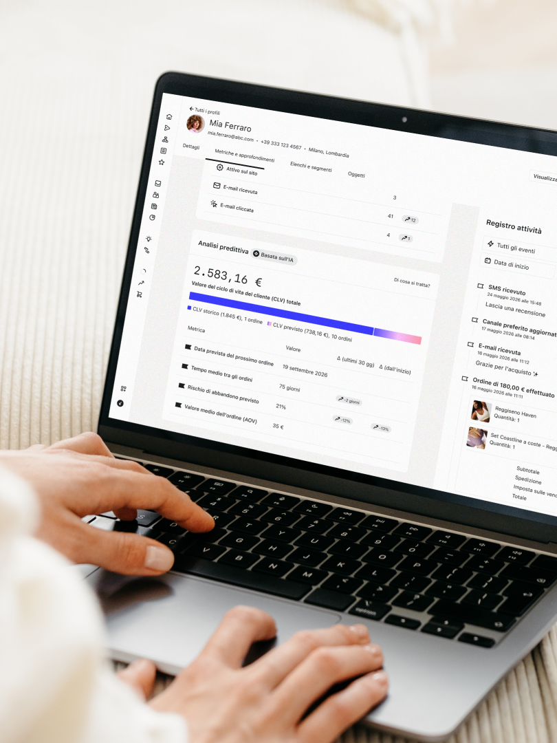 Una persona usa un laptop che mostra un profilo cliente, l'analisi predittiva e il registro delle attività.