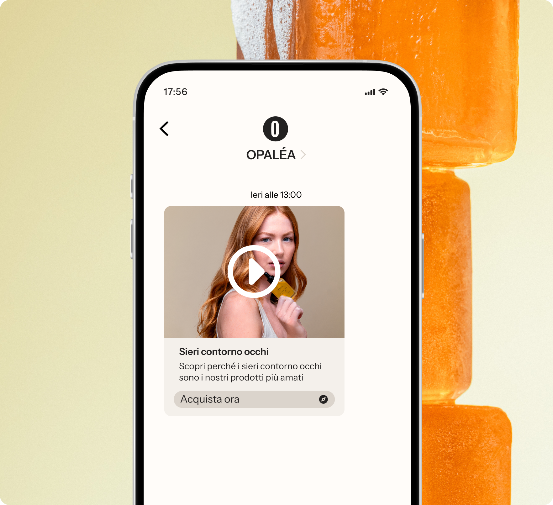 Smartphone displaying an Opalea app with a video thumbnail about eye serums, against a blurred background of orange popsicles.