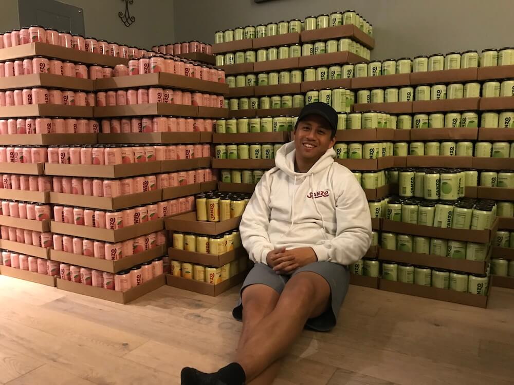 Image shows a Sanzo employee with cases of the soda. 
