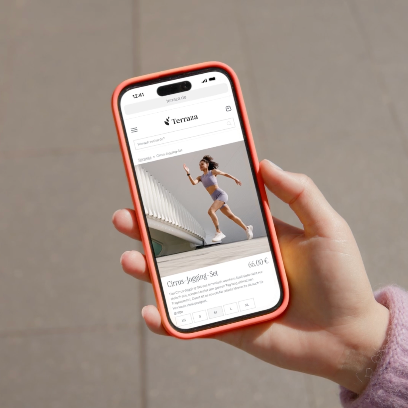 Hand holding a smartphone displaying a Terraza product page for a 'Cirrus Jogging-Set,' showing a woman running in a lavender athletic outfit.