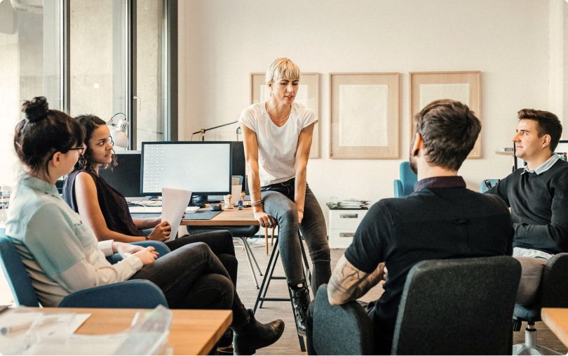 Five coworkers gather for a discussion in a bright, modern office.
