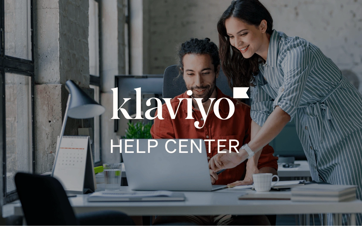 Two coworkers collaborate at a laptop in an office, overlaid with the Klaviyo Help Center logo.