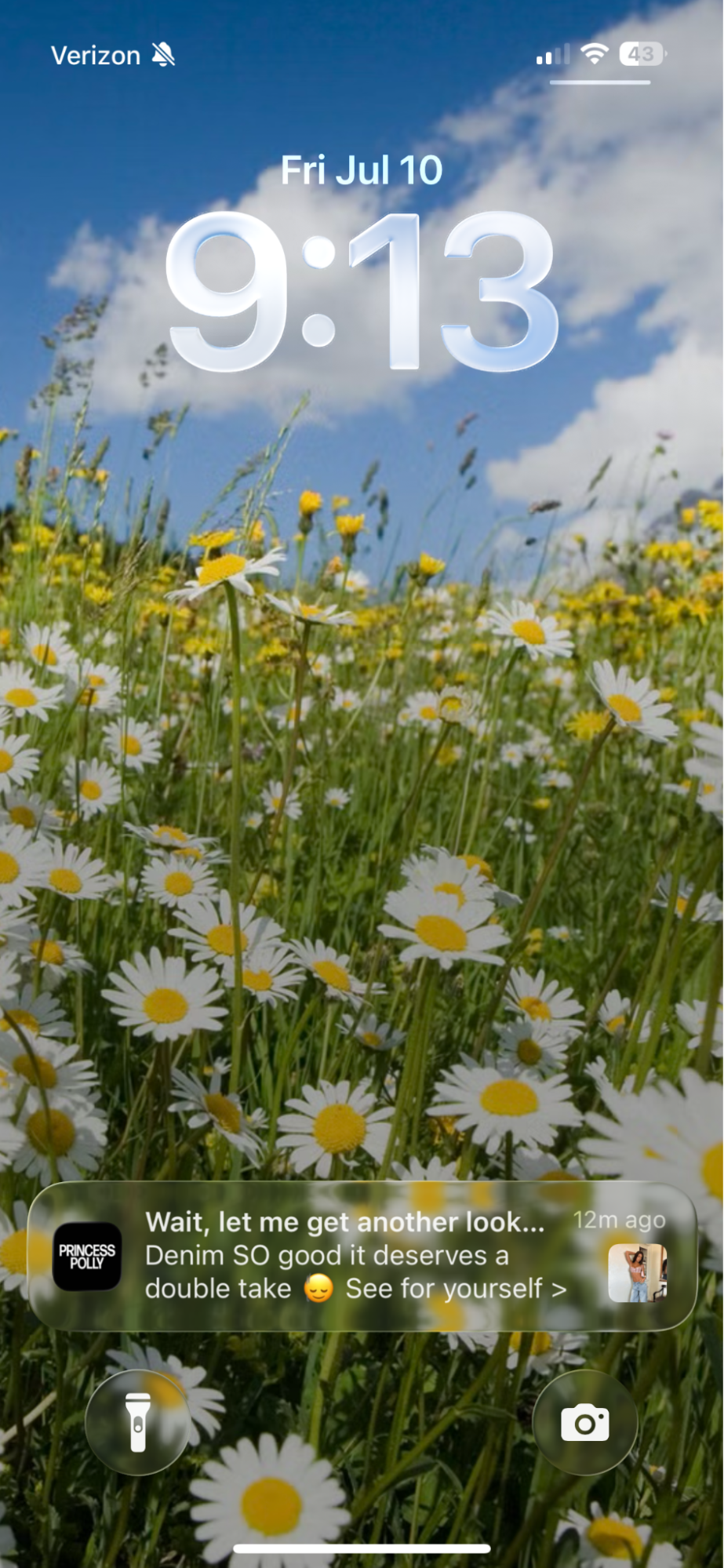 iPhone lock screen displaying 9:13 on a wallpaper of a field of daisies under a blue sky, with a Princess Polly notification about denim.