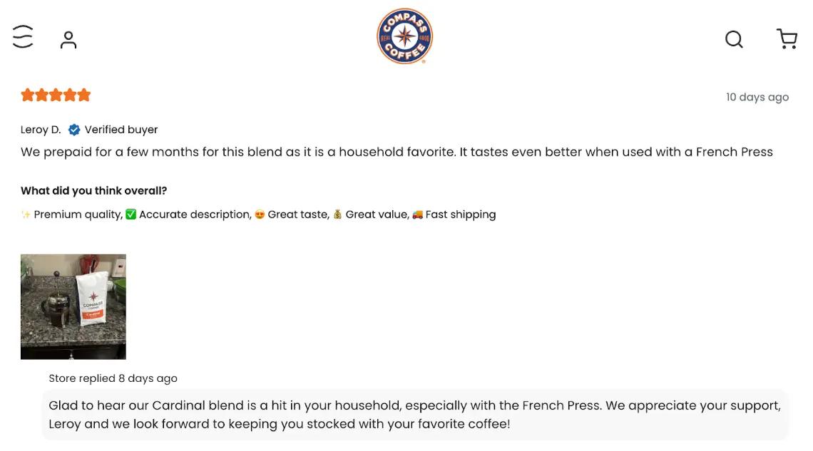 Image shows a screenshot of the Compass Coffee website, with a 5-star review from a customer for their Cardinal blend. The review reads, “We prepaid for a few months for this blend as it is a household favorite. It tastes even better when used with a French Press.” The review includes a photo of the product in the customer’s kitchen, and a response from the brand that reads, “Glad to hear our Cardinal blend is a hit in your household, especially with the French Press. We appreciate your support Leroy and we look forward to keeping you stocked with your favorite coffee!”